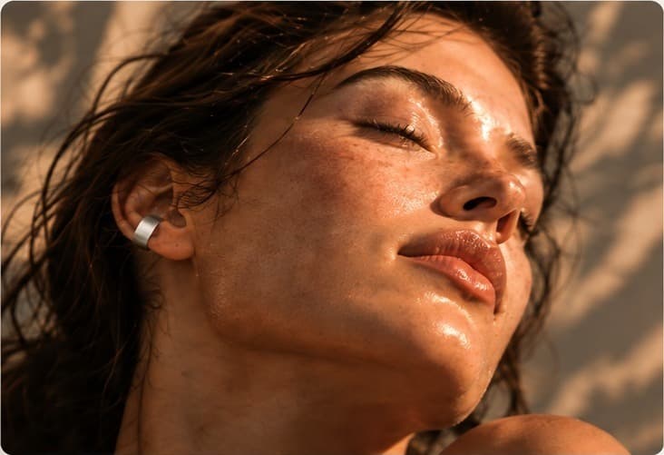 A woman in low sun wearing the Dao ear cuff, eyes closed.